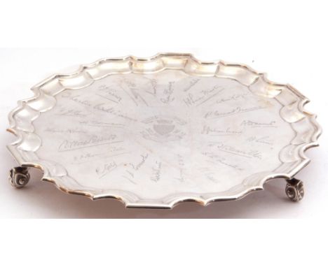 George V presentation silver salver, a round body with a Chippendale style border, standing on three shaped feet, the centre 