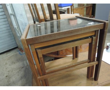 A vintage nest of teak and smoked glass tables