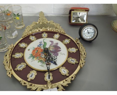 A wall clock with floral decoration, a bakelite alarm clock and a travel clock