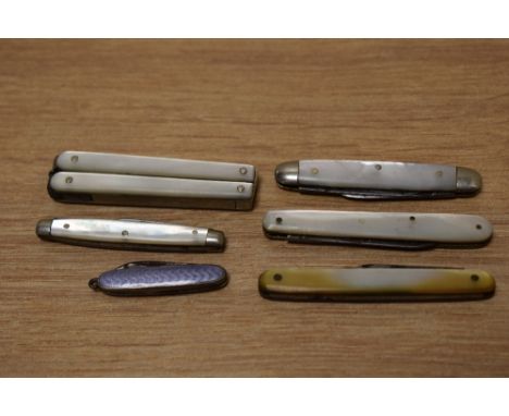 A selection of Mother-of- Pearl mounted pen knives and a miniature lilac guilloche enamel example.
top left hand item is a pa