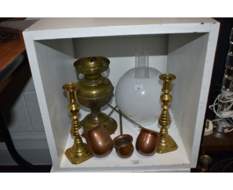 An assorted collection of brass and copperware, including an early 20th Century oil lamp with shade, and spirit ladles