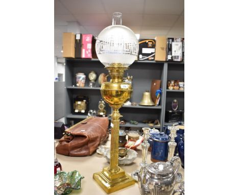 A Victorian oil lamp having ridged brass column over stepped foot, with frosted glass shade having Greek key pattern.