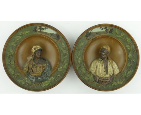 A pair of German relief plaques,
with portrait studies within holly decorated borders, impressed Musterschutz, 12".