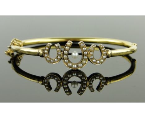 A Victorian unmarked yellow metal pearl set hinged bangle.