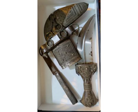 An Omani Khanjar knife with white metal scabbard and decoration to the hilt with geometric designs, a smaller attached smalle