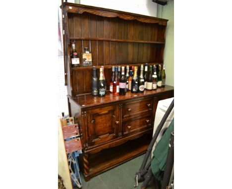 A dark oak dresser two drawers, two cupboard doors over open under tier. Barley twist fore legs. Three shelf plate rack&nbsp;