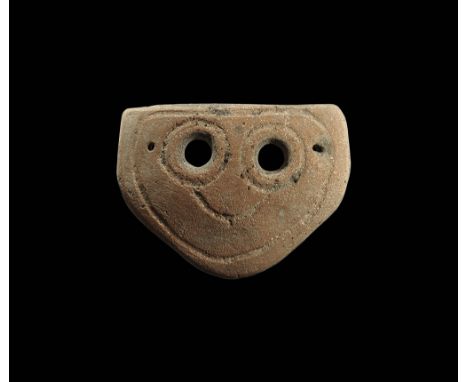 4th-3rd century BC. A trapezoidal ceramic mask with two eye-holes and incised stylised facial details; pierced for attachment