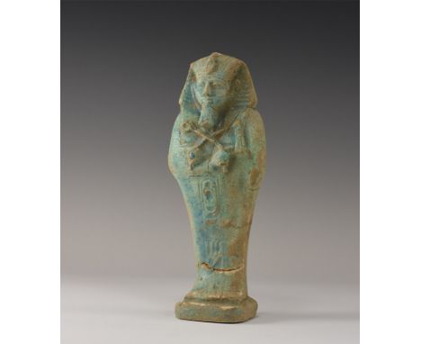 20th century AD. A blue glazed composition shabti with Nemes headdress, tools in the crossed hands, hieroglyphs to the lower 