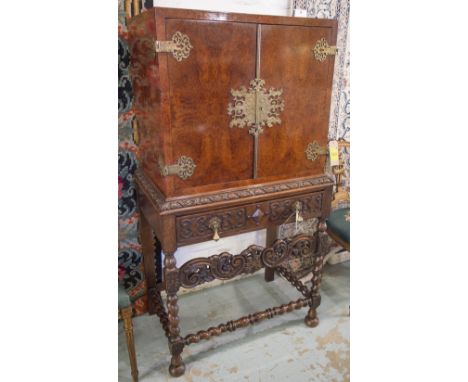 CABINET ON STAND, early 20th century amboyna with two doors enclosing a cellarette, tray and shelf, on a Jacobean style carve