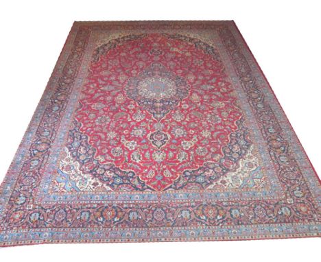 VINTAGE KASHAN CARPET, 407cm x 300cm, pendant medallion on a ruby field of scrolling vines and palmettes within corresponding