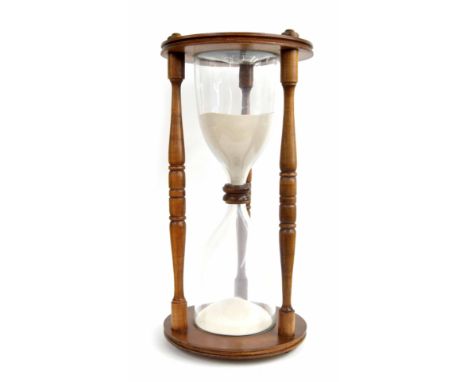 Hourglass sand timer, the twin flasks contained within an oak case united by three baluster turned columns and circular ends,