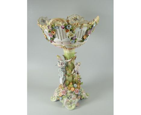 A colourful Continental ceramic two-piece comport in the manner of Meissen applied with two figures and raised flowers on a s