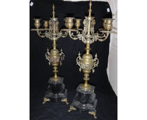 A pair of 19th Century brass four branch candelabra, the four branches uniting on a turned and carved brass body, raised on a