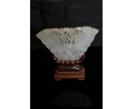 A carved Chinese jade butterfly plaque with carved hardwood stand