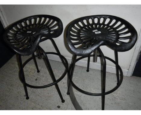 A pair of modern iron tractor seat stools with adjustable seats *