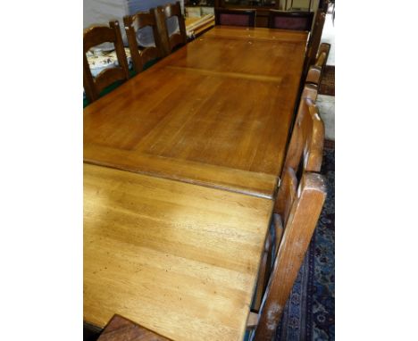 A modern oak farmhouse style kitchen table with two end leaves, together with a set of eight matching ladder back dining chai