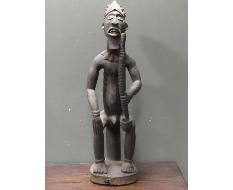 An African carved wood figure of a seated male smoking a pipe 109cm