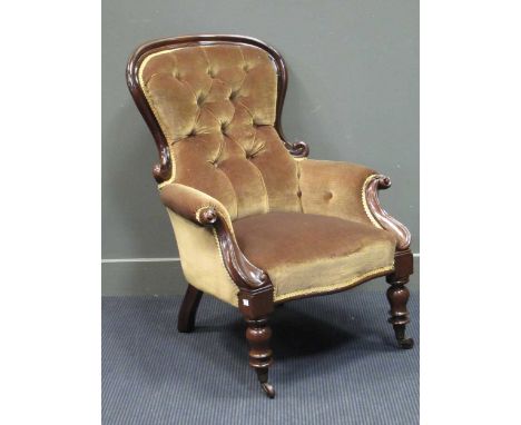 A mid-Victorian mahogany button back scroll carved armchair on turned legs and ceramic castors
