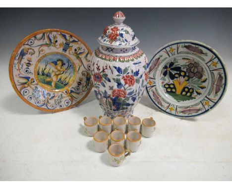 A continental pottery spirit barrel, modelled as a cherub, with nine cups; a Cantigali style plate and a Delft plate; a Delft