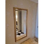 A gold framed bevelled dress mirror the carved frame with bead detailing surrounds a bevelled mirror