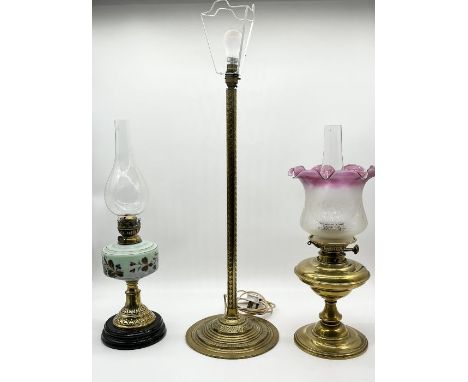 Two vintage oil lamps, one with modern cranberry shade, along with a brass column lamp