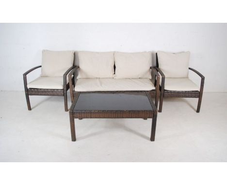 A rattan four piece garden suite consisting of a two seater sofa, two chairs and a coffee table