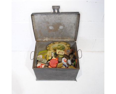 A black metal trunk containing a collection of various vintage tins