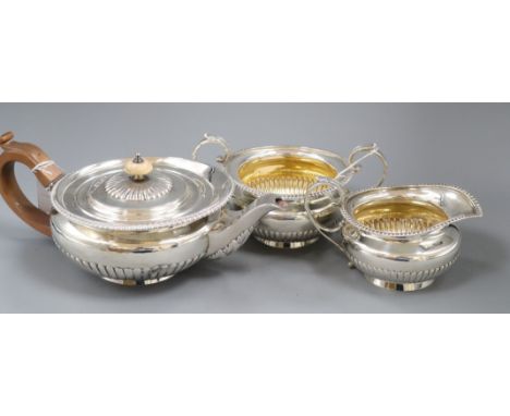 A matched silver three-piece tea service of flattened circular half-fluted form with gadrooned edges, the teapot by William E