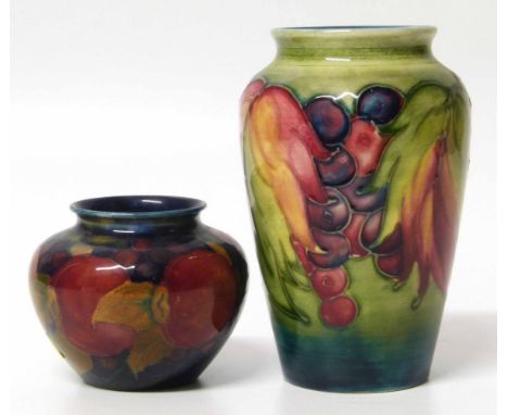 Moorcroft pomegranate vase and a leaf and berry pattern vase (small rim chip to the second vase) No condition reports for thi