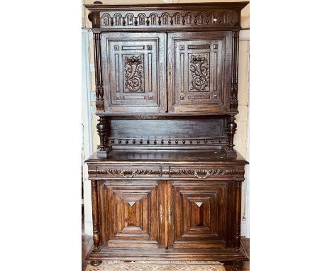 A 20th century oak dresser, moulded cornice above arch carved frieze, over twin panel carved doors, foliage carving throughou