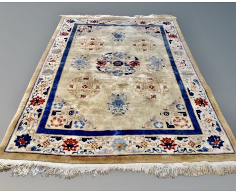 A Chinese floral embossed fringed carpet on gold ground, 325cm by 210cm.