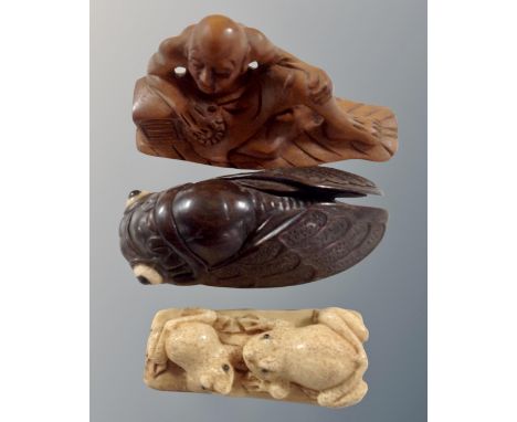 A carved fruit wood netsuke of a gentleman seated, two further netsukes depicting a locust and two frogs 