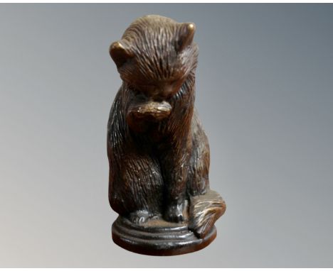 A bronze figure of a seated cat licking its paw, height 6cm 