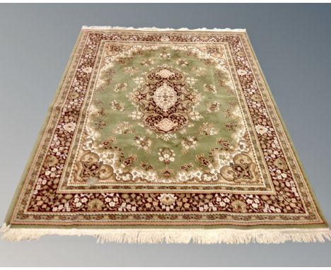 A machine made Persian design fringed carpet on green ground, 236cm by 170cm.