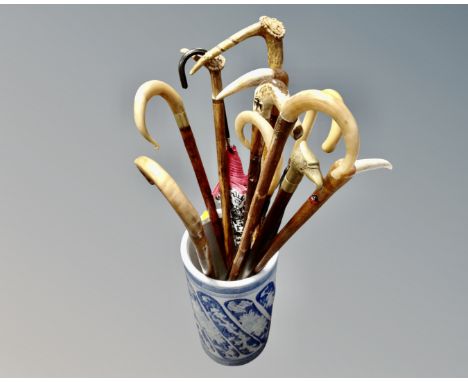 A blue and white ceramic stick pot containing a quantity of vintage walking sticks and umbrellas including horn handled examp