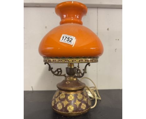 A vintage ceramic table lamp with orange glass shade