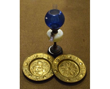 Victorian oil lamp having a pale green glass reservoir with decoration in relief, brass column and black glazed pottery base 