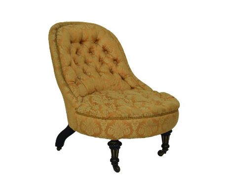 Victorian spoon back nursing chair upholstered in deep buttoned floral fabric and standing on ebonised and gilt tapered turne