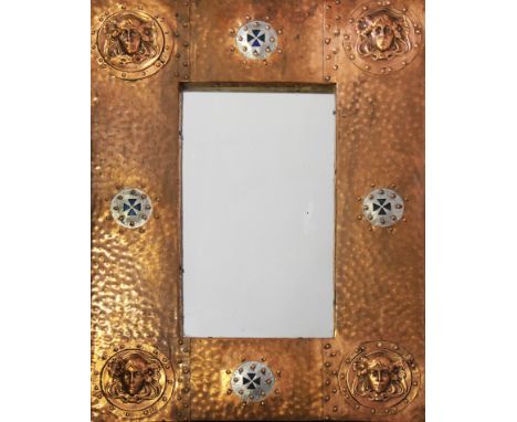 An arts and crafts hand beaten copper framed mirror with face masks to corners and enamel finished plates, 63cm x 46cm.