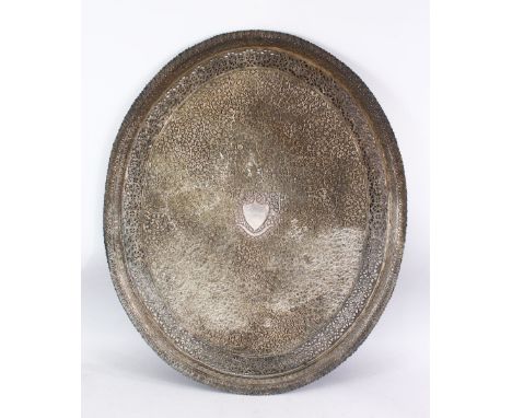A LARGE INDIAN SILVERED BRONZE OR BRASS TRAY, with a central crest and scrolling foliate, 68.5cm x 56.5cm