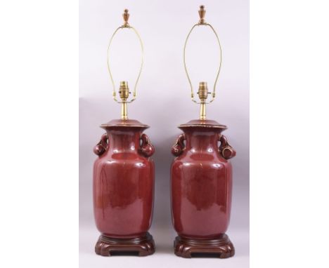 A GOOD LARGE PAIR OF CHINESE SANG DE BOEUF TWIN HANDLE LAMP VASES, the handles formed in the shape of fruit, both fitted with
