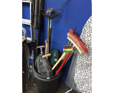 A dustbin containing various garden tools and brushes 