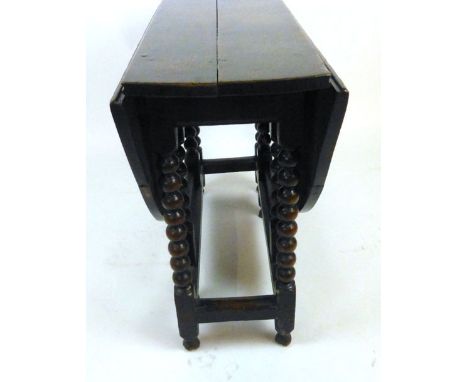 An 18th century oak gate leg table the oval top supported on two single gate actions with bobbin turned legs joined by moulde