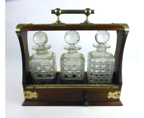 An early 20th century oak cased tantalus with silver plated mounts and three cut glass decanters, h. 32 cm, w. 36 cm, d. 13 c