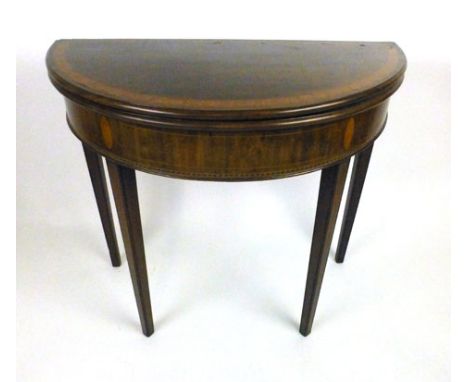 A late 18th century mahogany, tulipwood crossbanded and boxwood line inlaid demi-lune card table, the fold over top supported