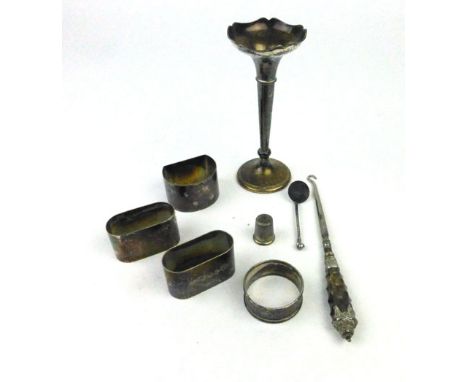 A parcel of silver hallmarked items to include four napkin rings, thimble, a weighted bud vase and a button hook (8)