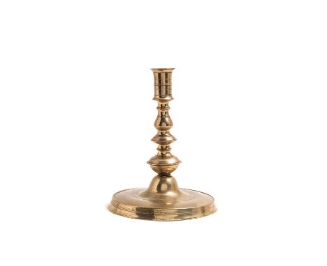 

A large brass candlestick, dated 1612
The date engraved on the knop, the circular base associated but earlier in date, 17.5