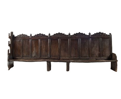 A large West Country oak wall settle, circa 1550
With plank seat and ten plain panels surmounted by arched crest-panels of Re