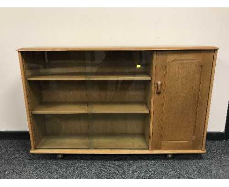 An Ercol elm sliding door bookcase