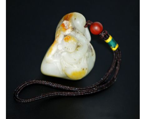 A jade toggle of a curious monkey holding a peach,  crouching over a stone. 2in X 2in 102g